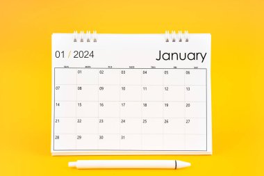 Ocak 2024, 2024 yılı için aylık masa takvimi ve sarı arkaplan üzerine kalem.