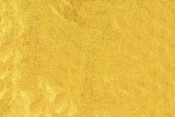 Gold foil texture background with highlights and uneven surface.
