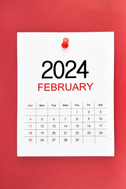 Şubat 2024 takvim sayfası kırmızı zemin üzerinde pin basın.