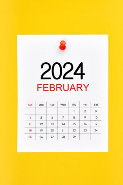 Şubat 2024 takvim sayfası sarı zemin üzerinde pin basın.