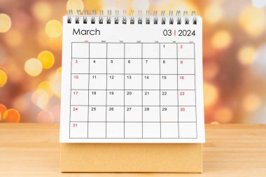Mart 2024 Masa takvimi ahşap masa üzerinde altın ışıklı bokeh arka plan.