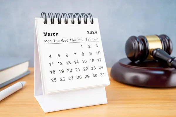 Desk calendar for March 2024 and judge\'s gavel on the worktable.