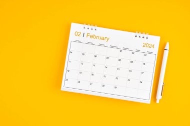 Şubat 2024, 2024 yılı için aylık masa takvimi ve sarı arkaplan üzerine kalem.