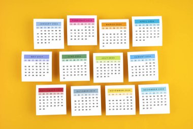 Aylar 1-12 Ocak-Aralık 2024 takvim sayfası sarı arkaplan üzerine.