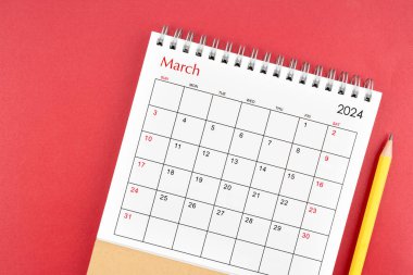 Mart 2024 kırmızı arkaplan üzerinde masa takvimi ve kalem.