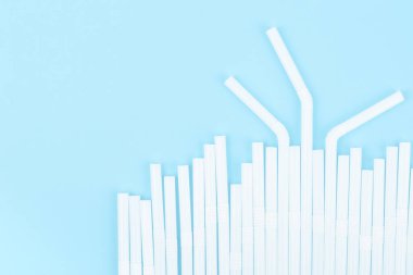 Mavi arkaplanda beyaz plastik içme çubuğu grubu