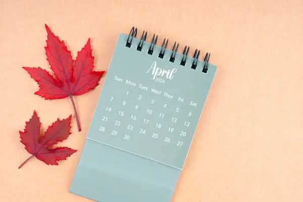 April 2024 monthly calendar and fall leaves on brown background.