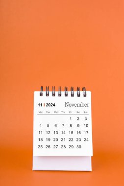 Turuncu arkaplandaki Kasım 2024 tablo takvimi dikey.