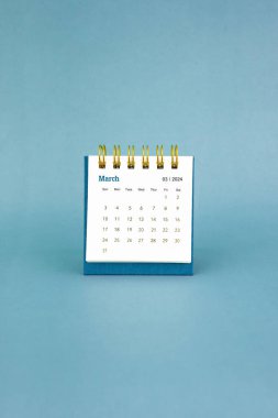 Mart 2024 mavi arkaplan üzerine beyaz masa takvimi.