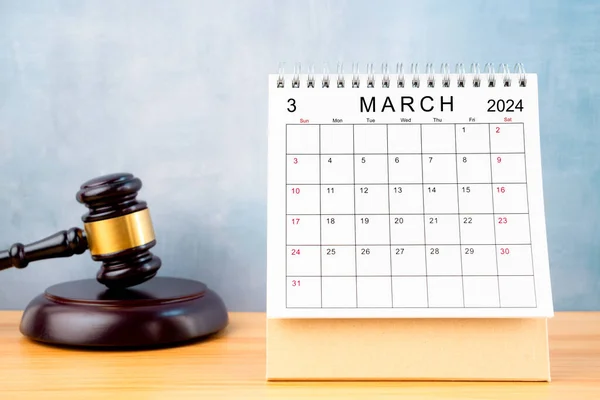 Desk calendar for March 2024 and judge\'s gavel on the worktable.
