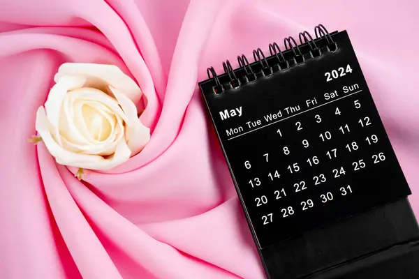 stock image May 2024 desk calendar black color and rose on pink textile background.