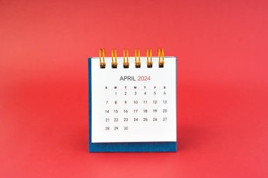 Nisan 2024 kırmızı arkaplanda beyaz masa takvimi.