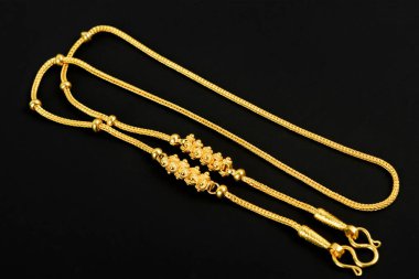 Siyah arkaplanda altın bir kolye.