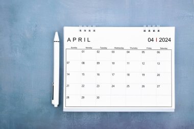 Nisan 2024 masa takvimi ve mavi ahşap arka plan üzerindeki kalem görünümünün tam üstünde.