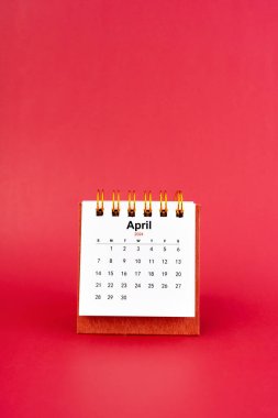 Nisan 2024 kırmızı arkaplan üzerine beyaz küçük masa takvimi.
