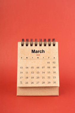 Mart 2024 kırmızı arkaplan üzerine beyaz masa takvimi.