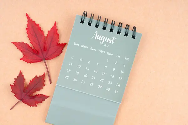 August 2024 monthly calendar and fall leaves on brown background.