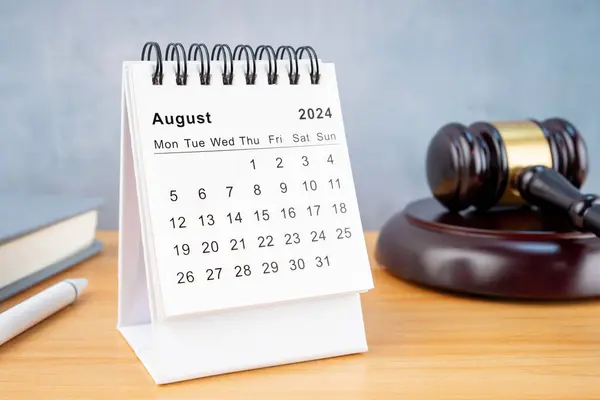 Desk calendar for August 2024 and judge\'s gavel on the worktable.