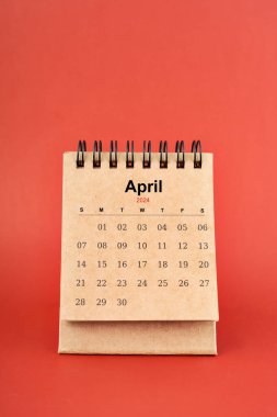 Nisan 2024 kırmızı arkaplan üzerine beyaz küçük masa takvimi.