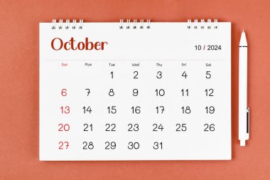 Ekim 2024 2024 Aylık masa takvimi ve kırmızı arkaplan üzerine kalem.