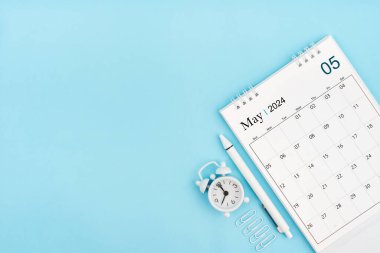Mayıs 2024, 2024 için aylık masa takvimi ve mavi arka planda ataçları olan çalar saat. Kopyalama alanı olan konum.