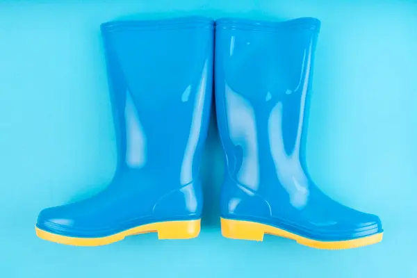 Pair of blue rubber boots on blue color background,