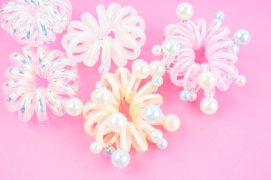 Pembe arkaplanda renkli plastik saç lastikleri.