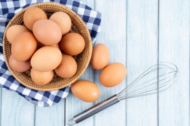 Mavi ahşap zeminde ahşap sepette organik tavuk yumurtası..