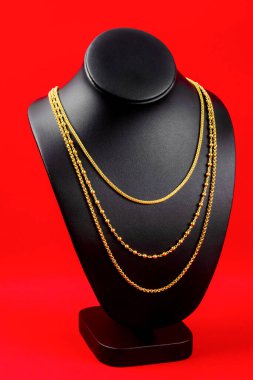 Kolye standı kırmızı kadife kumaşın üzerinde altın kolyeyle.