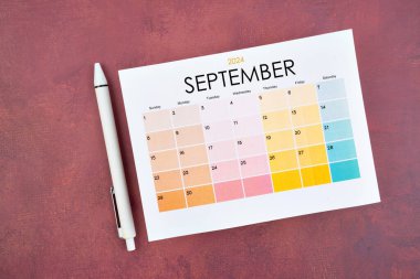 Eylül 2024 takvim sayfası ve kırmızı renk retro arkaplanı üzerine kalem.