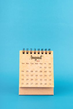 Mavi arkaplanda Ağustos 2024 beyaz masa takvimi.