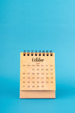 Ekim 2024 mavi arkaplan üzerine beyaz masa takvimi.