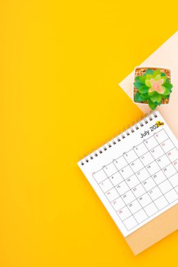 Calendar page for July 2024 and houseplant on yellow background, planning concept. clipart