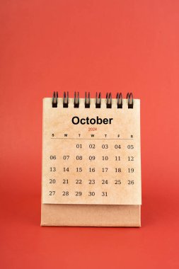 Ekim 2024 kırmızı arkaplan üzerine beyaz masa takvimi.