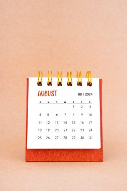 Kahverengi arkaplanda Ağustos 2024 beyaz masa takvimi.