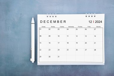 Aralık 2024 masa takvimi ve mavi ahşap zemin üzerindeki kalem görünümünün hemen üstünde.