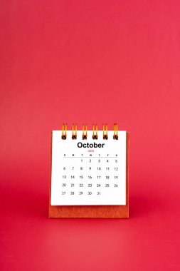 Ekim 2024 kırmızı arkaplan üzerine beyaz masa takvimi.
