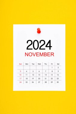 Kasım 2024 takvim sayfasında sarı arkaplan üzerine iğne basma.