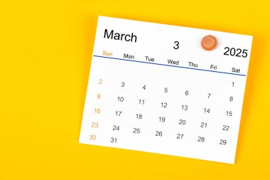 Mart 2025 ve sarı zemin üzerinde ahşap pim.