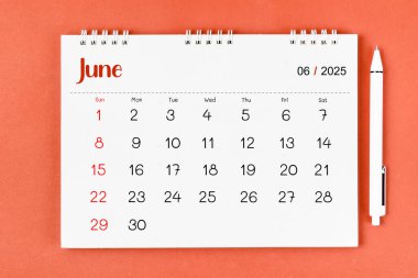 2025 Haziran ayının masa takvimi ve kırmızı arka planda bir kalem..