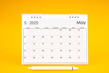 Mayıs 2025, 2025 yılı için aylık masa takvimi ve sarı arkaplan üzerine kalem.
