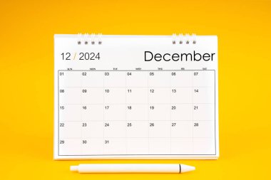Aralık 2024, 2024 yılı için aylık masa takvimi ve sarı arkaplan üzerine kalem.