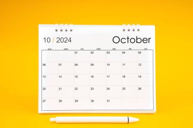 October 2024, Monthly desk calendar for 2024 year and pen on yellow color background. clipart