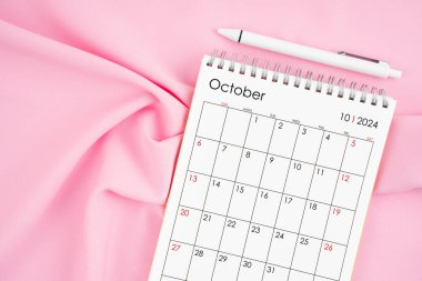 Ekim 2024 takvim ve pembe kumaşlı kalem. Aylık takvim kavramı.