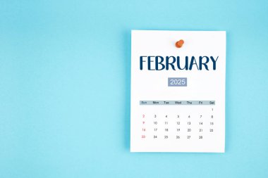 Şubat 2025 takvim sayfası mavi arkaplan üzerine pin basın.