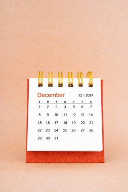 Aralık 2024 kahverengi arkaplan üzerine beyaz masa takvimi.
