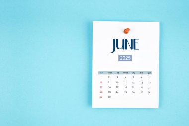 Haziran 2025 takvim sayfası mavi arkaplandaki iğneye basılı.