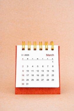 Mart 2025 kahverengi arkaplan üzerine beyaz masa takvimi.