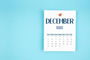 Aralık 2025 takvim sayfası mavi arkaplan üzerine pin basın.