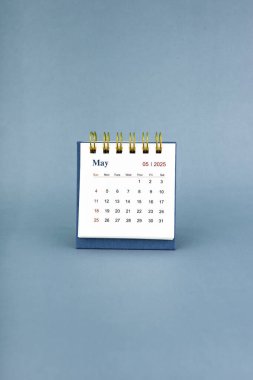 Mayıs 2025 mavi arkaplan üzerine beyaz masa takvimi.